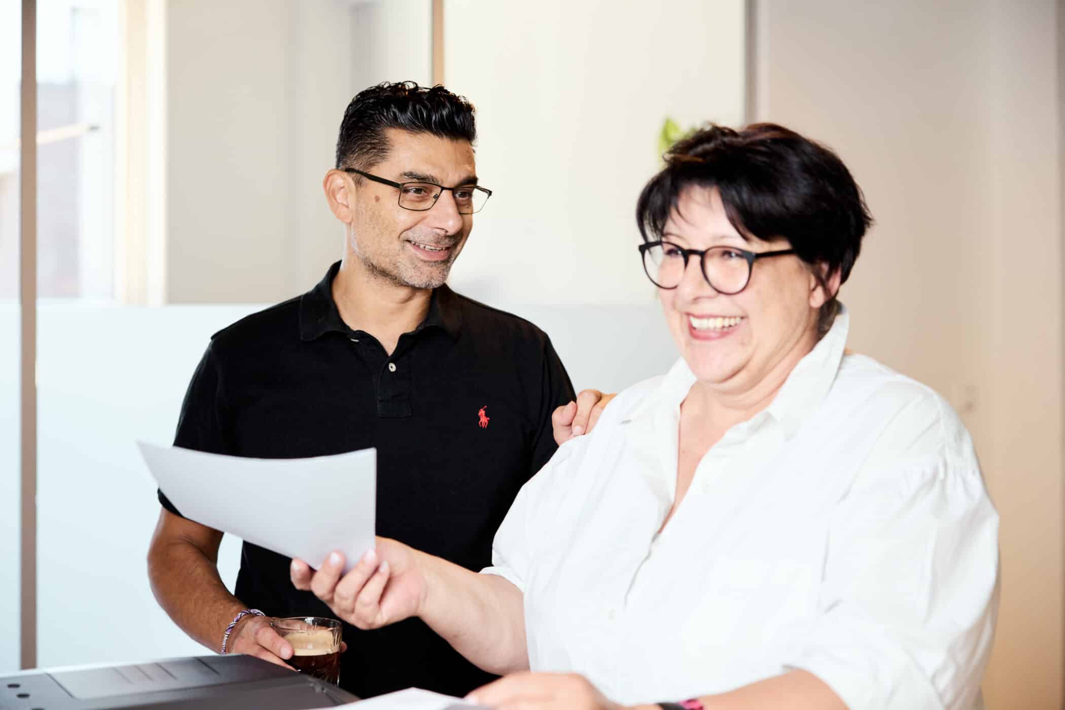 Eine Steuerfachangestellte und ein Steuerberater von MTA My Tax Advisor in Hamburg lachen gemeinsam bei der Arbeit